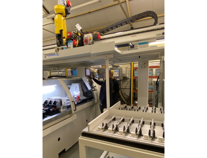 A space-saving gantry rail with a FANUC M-20iD/25 6-axis robot transfers parts between the three-machine cell A space-saving gantry rail with a FANUC M-20iD/25 6-axis robot transfers parts between the three-machine cell